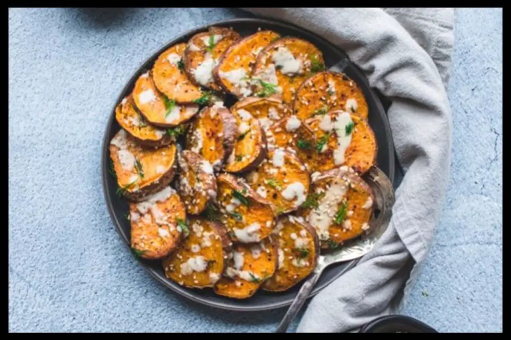 A picture of 30-Minute Sesame Roasted Sweet Potatoes in a black plate with a table clothes beside it.