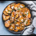 A picture of 30-Minute Sesame Roasted Sweet Potatoes in a black plate with a table clothes beside it.