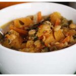 A picture of 30-Minute Squash Coconut Curry in a white bowl with a silver spoon in it.