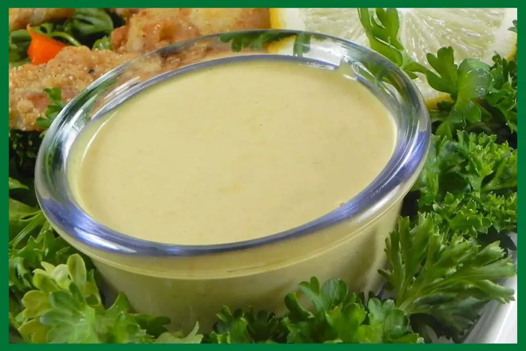 A picture of 5-Minute Honey Mustard Sauce in a glass bowl placed in the middle of lettuce leaves.