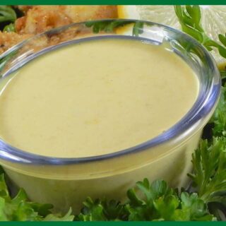 A picture of 5-Minute Honey Mustard Sauce in a glass bowl placed in the middle of lettuce leaves.