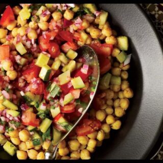 A picture of 5-Minute Spicy Chickpea Salad in a black plate with a spoon in it.