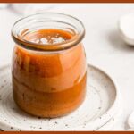 A picture of Vegan Caramel Sauce in a jar on a white plate