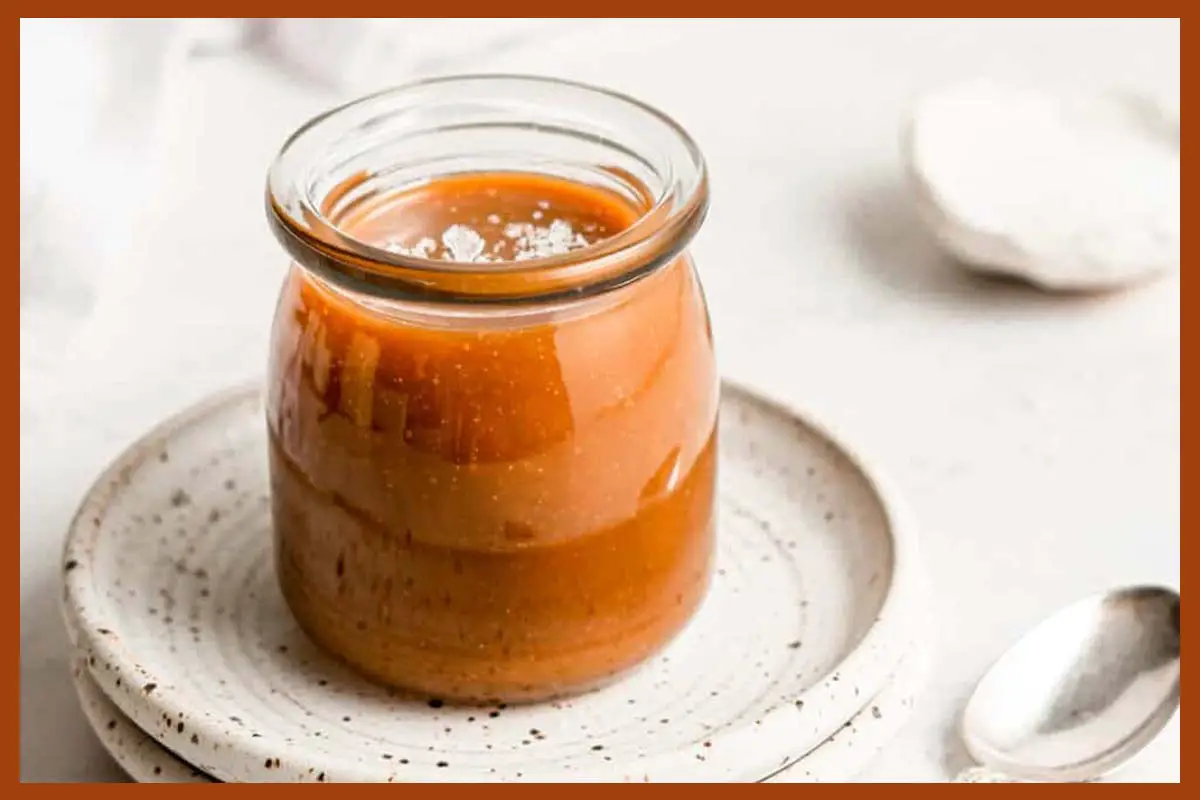 A picture of Vegan Caramel Sauce in a jar on a white plate