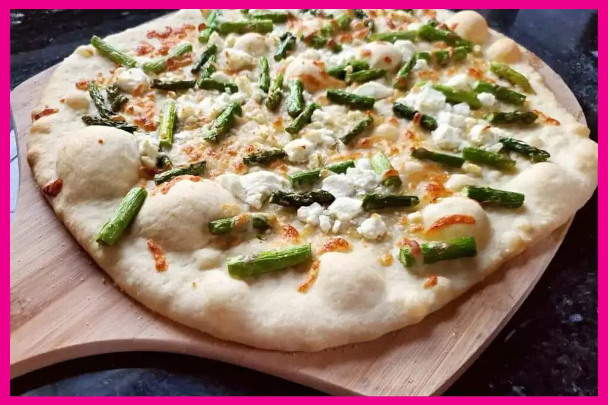 A picture of Asparagus Pea Goat Cheese Pizza on a wooden board.