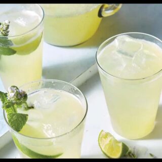 A picture of non-alcoholic margarita in 3 cups and pieces of lime in them and on the table.