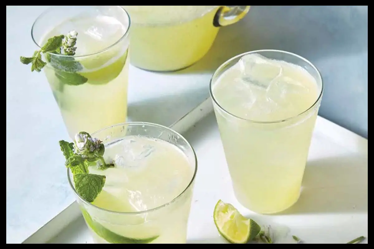 A picture of non-alcoholic margarita in 3 cups and pieces of lime in them and on the table.