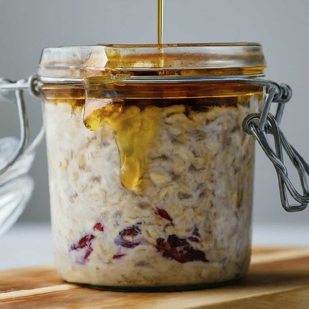 A picture of honey being poured into a jar filled with Overnight Oats