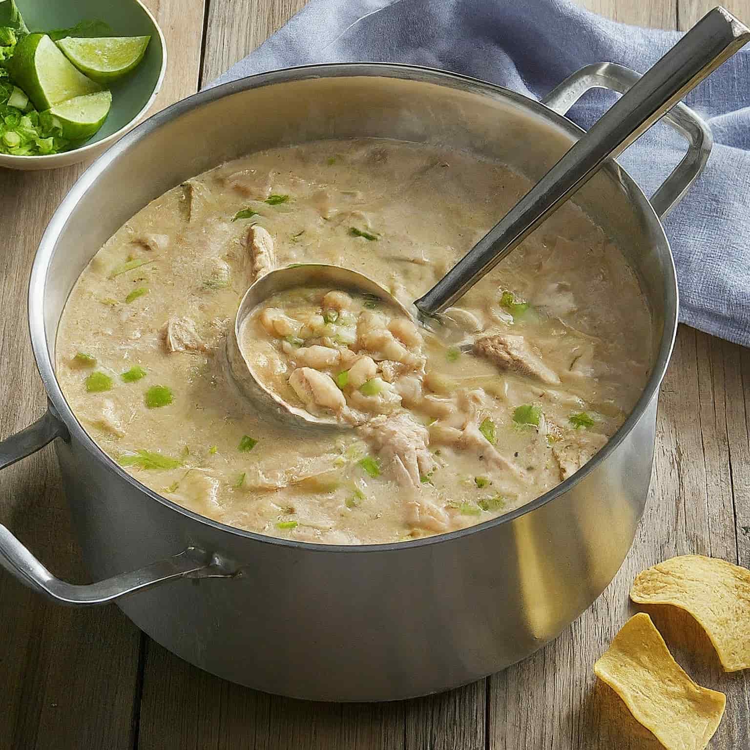 White Chicken Chili in a stainless steel pot with a ladle in it.