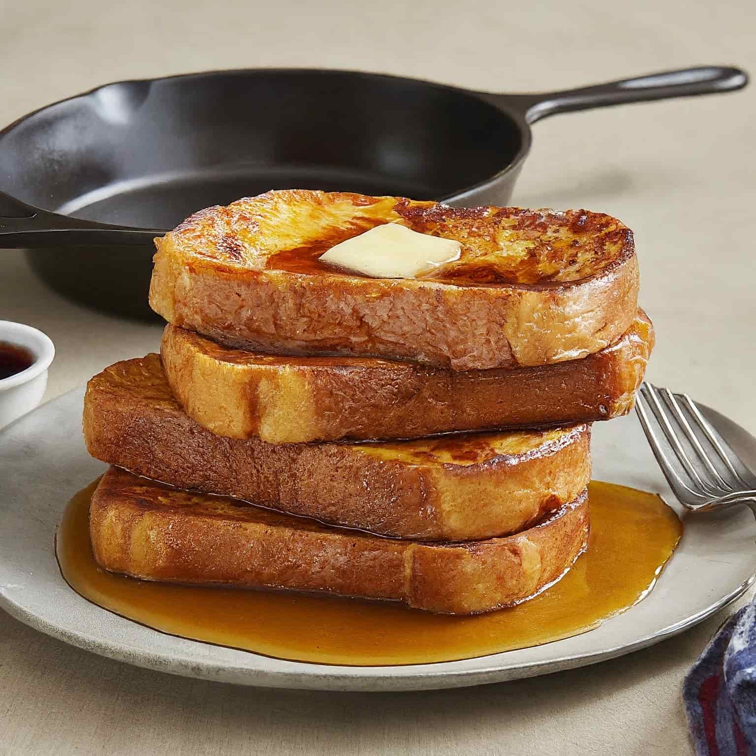 4 slices of Stovetop French Toast on a white plate with a piece of melting butter on it.
