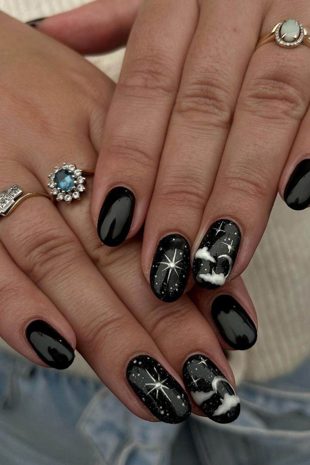 Black celestial nails with clouds and stars on an Almon nail shape